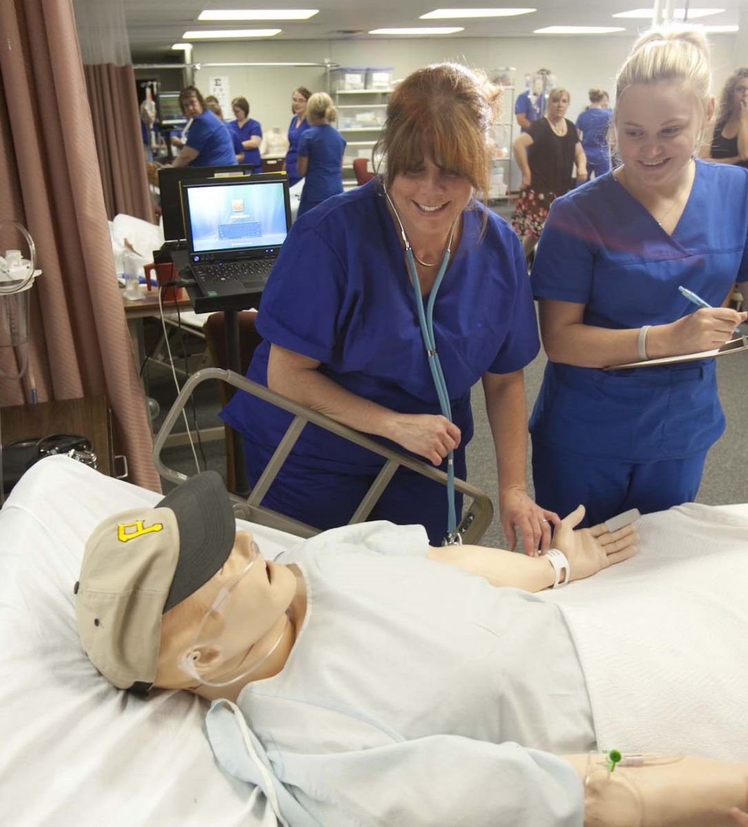 Two female Nursing students practicing skills on a simulation mannequin