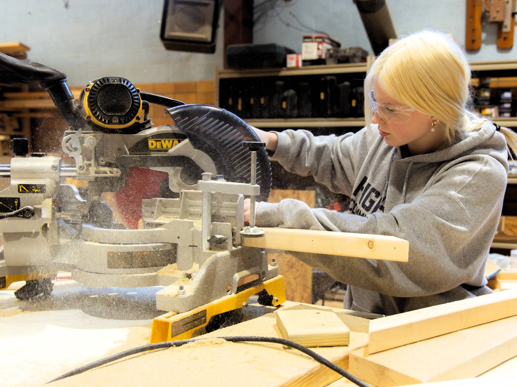 Construction technology student using a machine to cut wood.