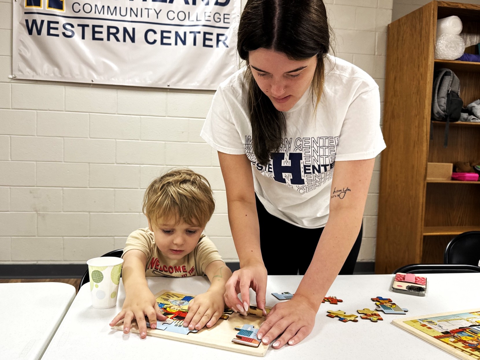 Student working with a child to put together a puzzle.
