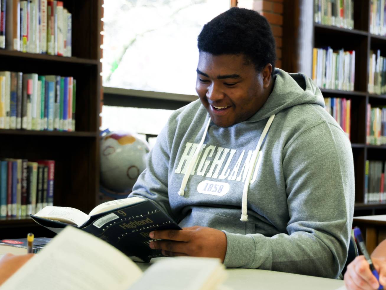 Student sitting in the library reading a book.