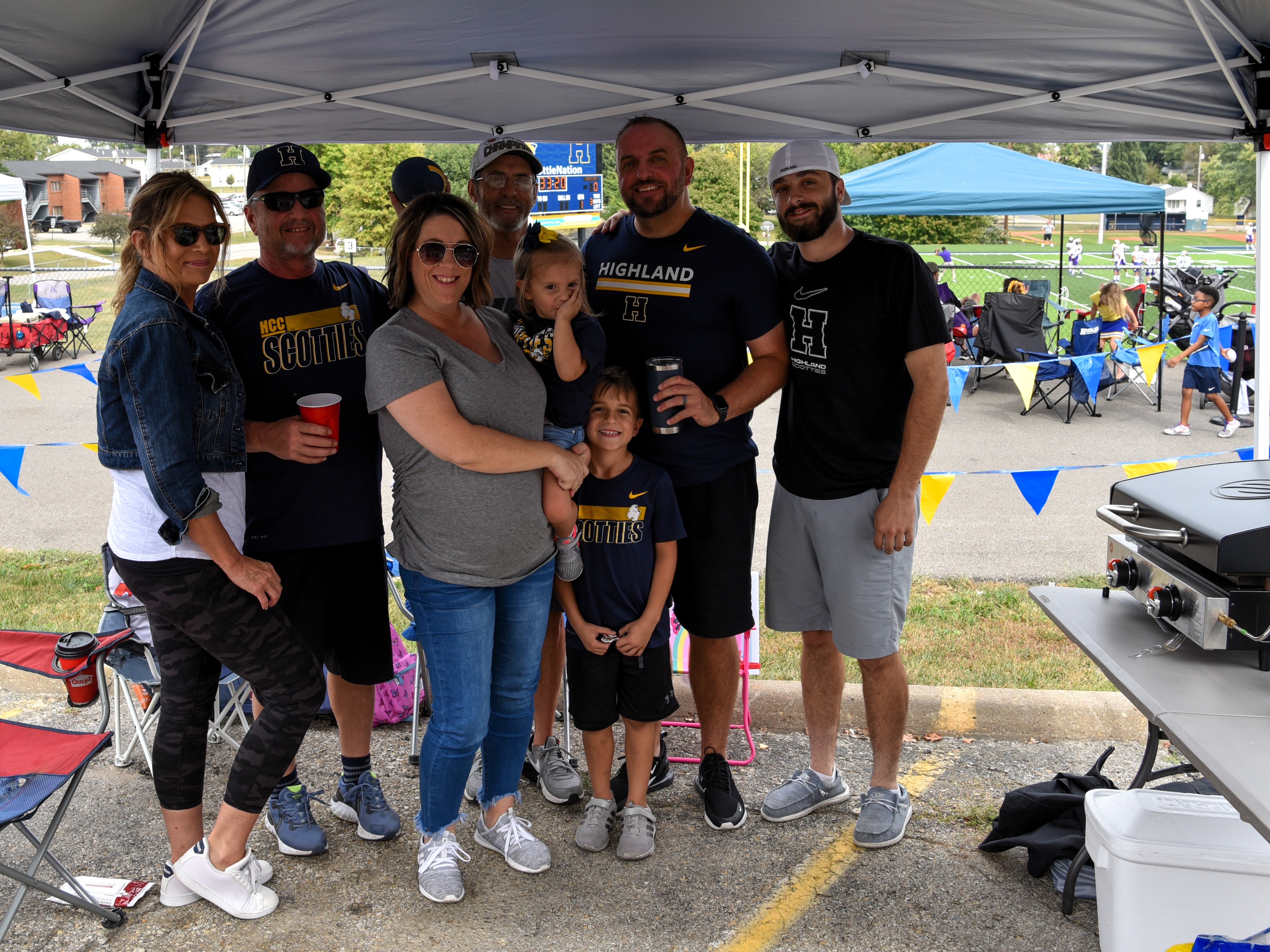 Group of alumni pose together while outside tailgating at a football game
