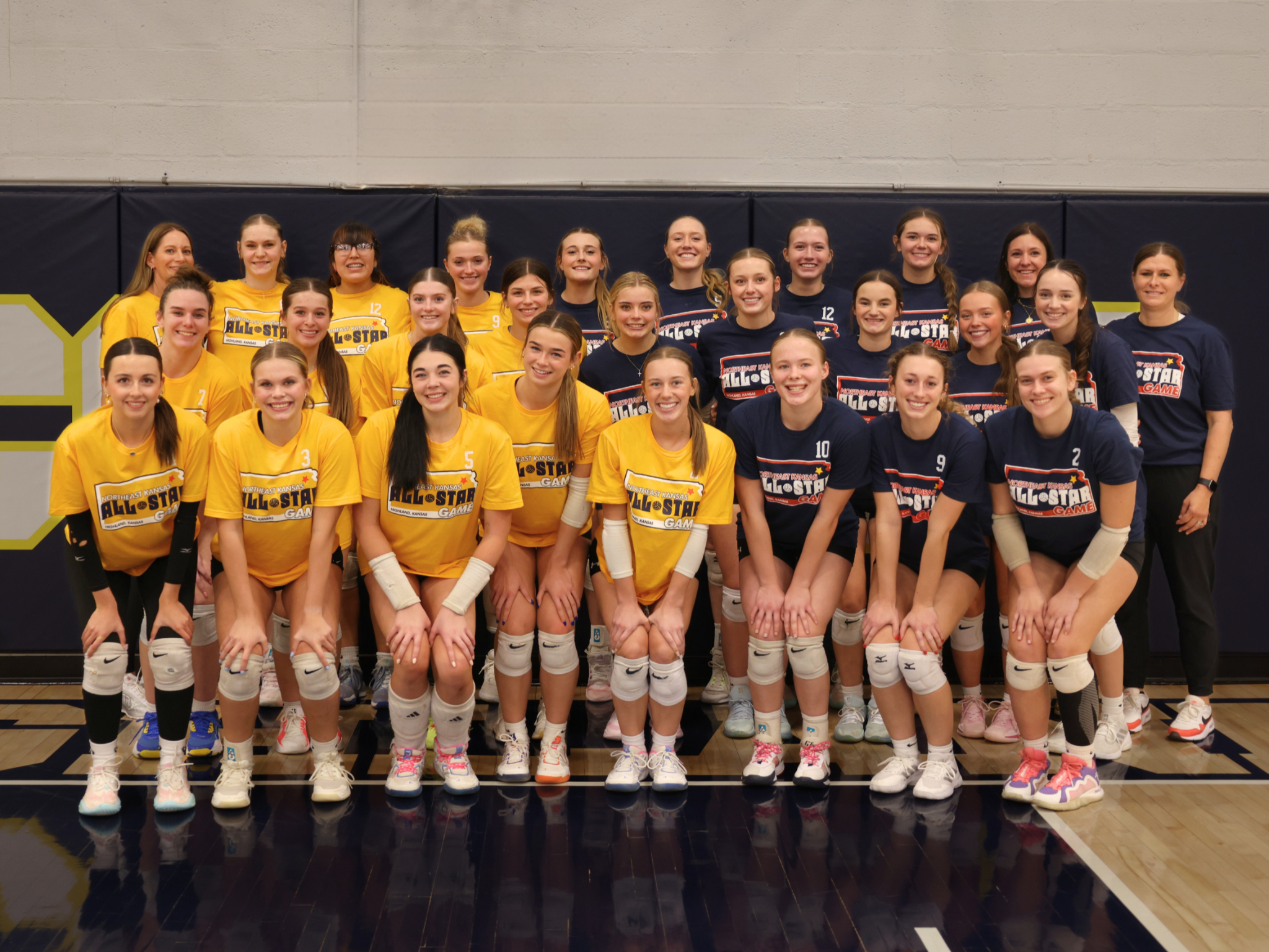 Group photo of the 2025 All-Star Volleyball players. Players are wearing yellow or navy tshirts.