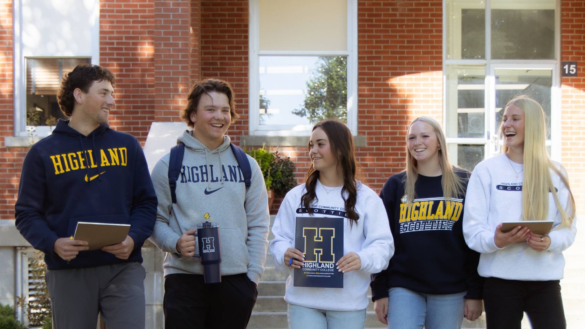 Group of 5 Students outisde holding Highland branded materials