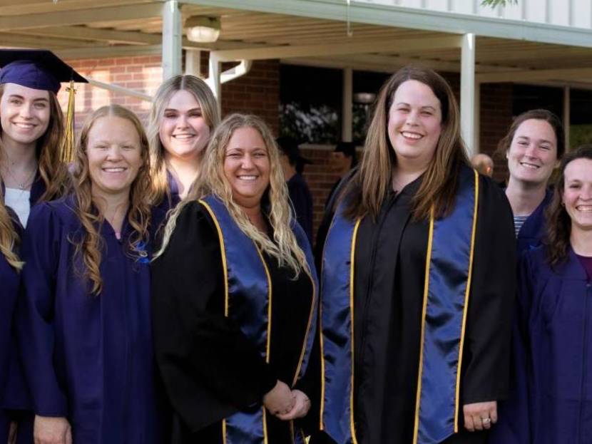 Two technical center faculty pose with graduating students